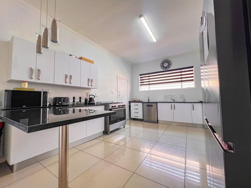 Modern kitchen featuring white cabinetry, black granite countertops, gas stove, and tiled flooring with ample workspace and integrated appliance connections.