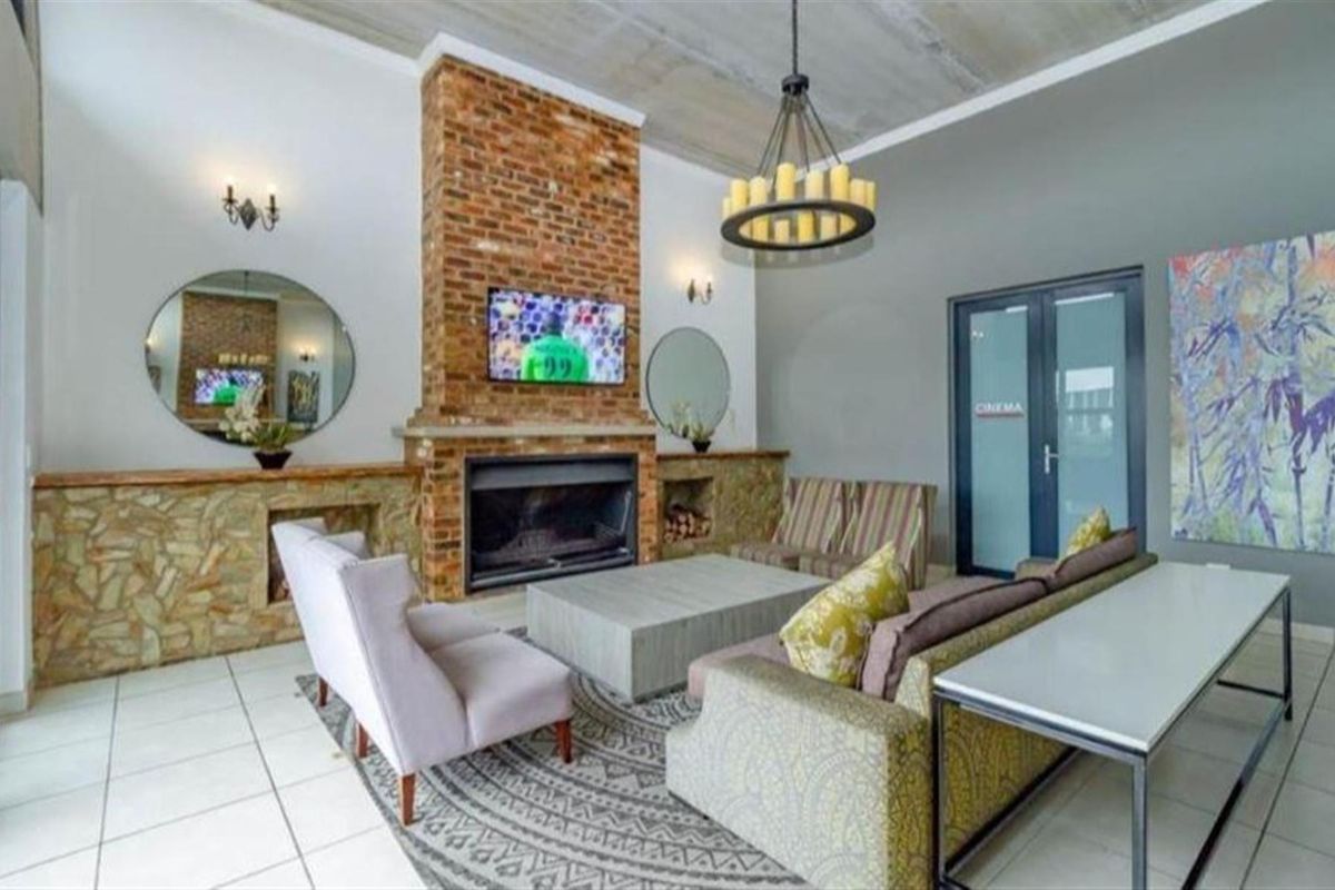 Spacious living area featuring a prominent brick fireplace with stone cladding, tiled floors, and an exposed concrete ceiling, creating a warm and inviting atmosphere.
