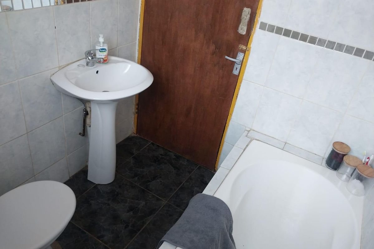 A functional bathroom featuring a pedestal basin, a built-in bathtub, and tiled wall finishes.