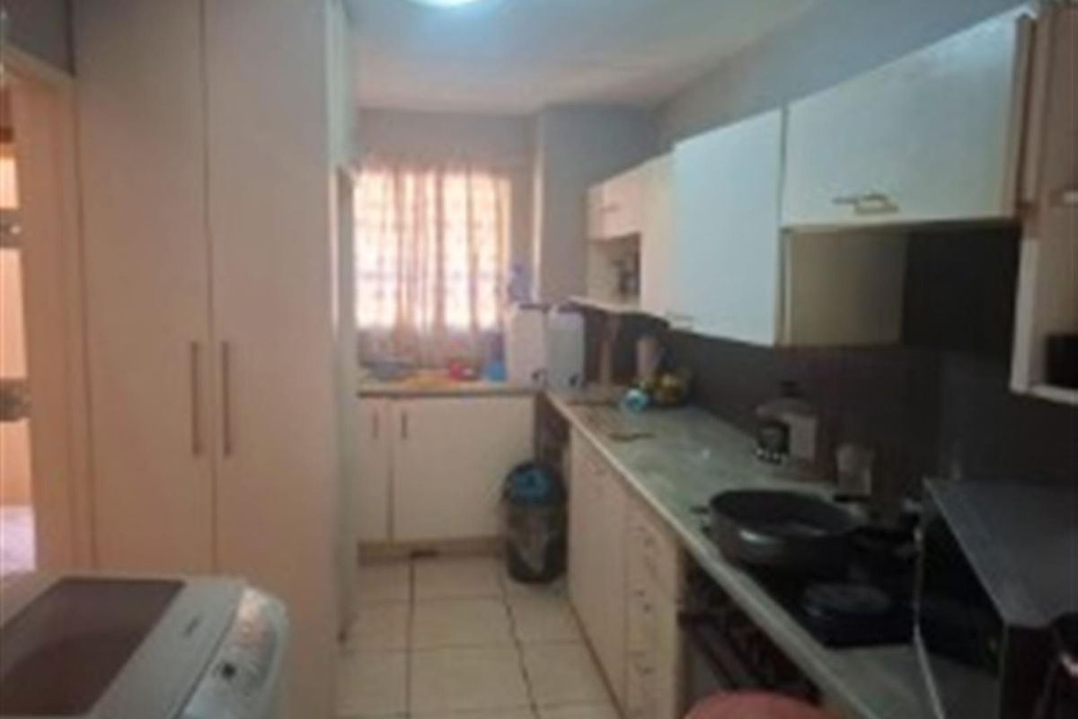 A functional galley-style kitchen featuring built-in cabinetry, a stove, and tiled flooring, offering a practical layout for daily meal preparation.