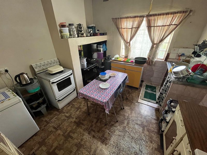 A dated kitchen featuring a built-in stove alcove, basic cabinetry, and tiled splashbacks, offering potential for a modern renovation.