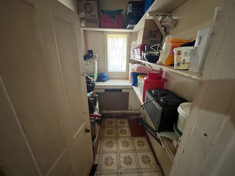 A small, functional scullery or pantry area featuring built-in shelving and a window, providing additional storage space for the home.