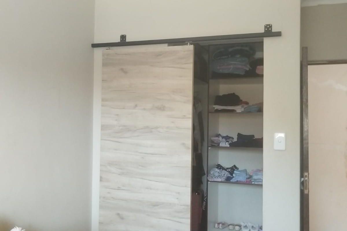 A bedroom featuring a built-in closet with a modern sliding barn-style door and internal shelving.