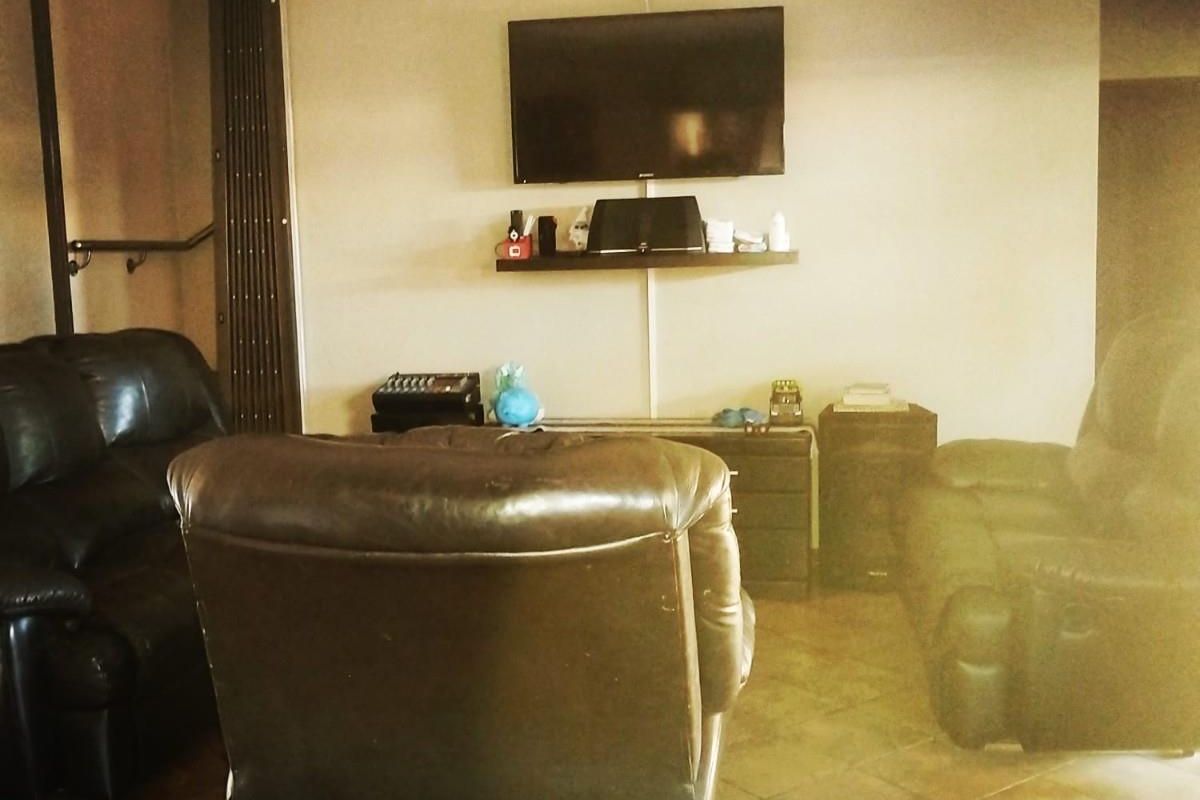 A living room featuring tiled flooring and a wall-mounted television setup.
