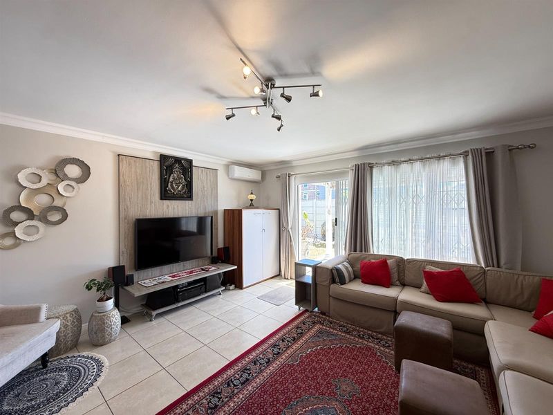 A well-maintained living room featuring tiled flooring, a split-system air conditioner, and a sliding glass door providing access to the exterior.