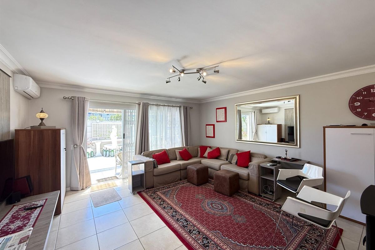 Spacious living room featuring tiled flooring, a split-system air conditioner, and a sliding glass door providing direct access to the outdoor patio area.