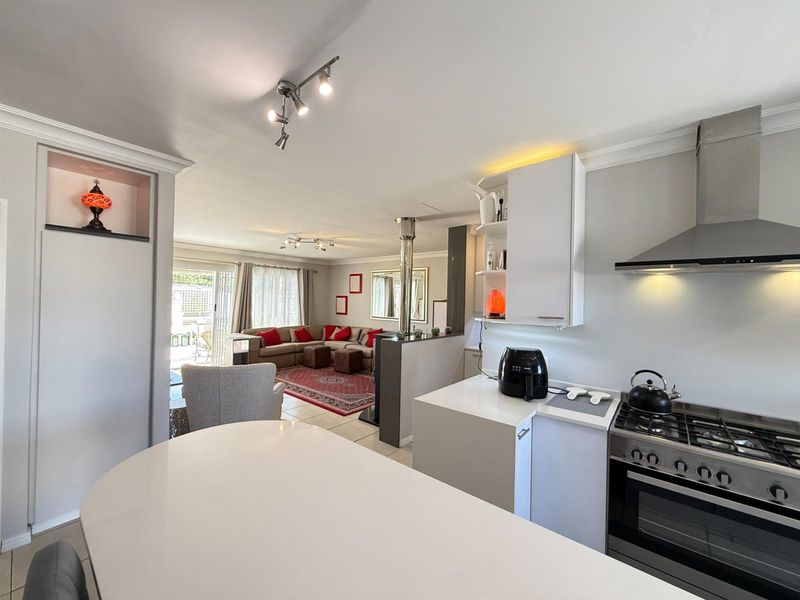 Spacious open-plan living and kitchen area featuring modern cabinetry, gas stove, quartz countertops, and seamless flow to the outdoor patio through sliding doors.