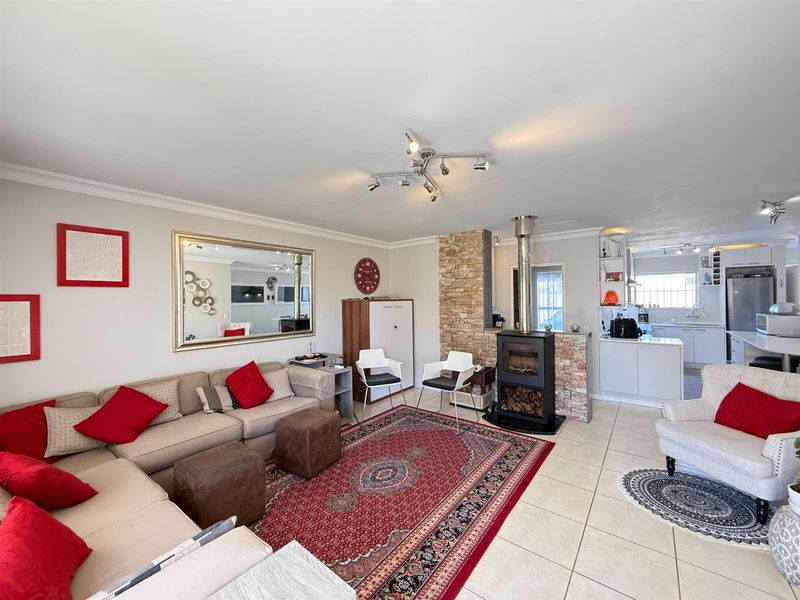 Spacious open-plan living area featuring a stone-clad fireplace, tiled flooring, and a modern kitchen with integrated cabinetry and island.
