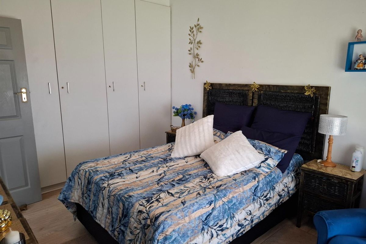 A bedroom featuring built-in floor-to-ceiling wardrobes and light-toned flooring.