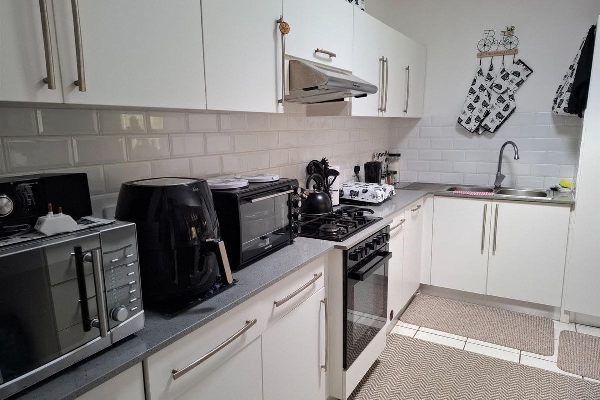 A functional kitchen featuring white cabinetry, subway tile backsplash, stone-look countertops, a built-in gas hob, and an integrated extractor fan.