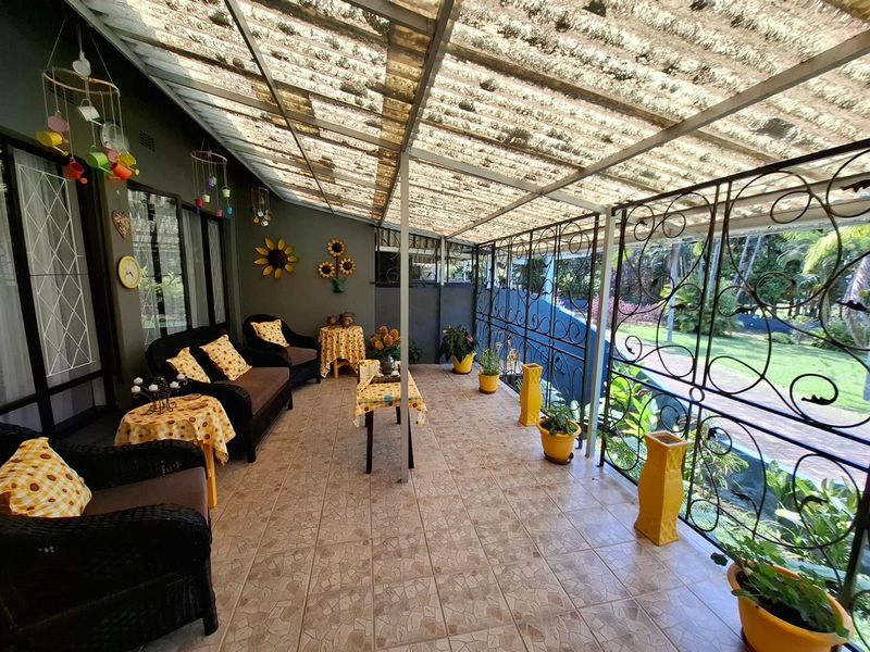 A covered patio area featuring tiled flooring, decorative wrought iron security screening, and a translucent roof structure overlooking the garden.