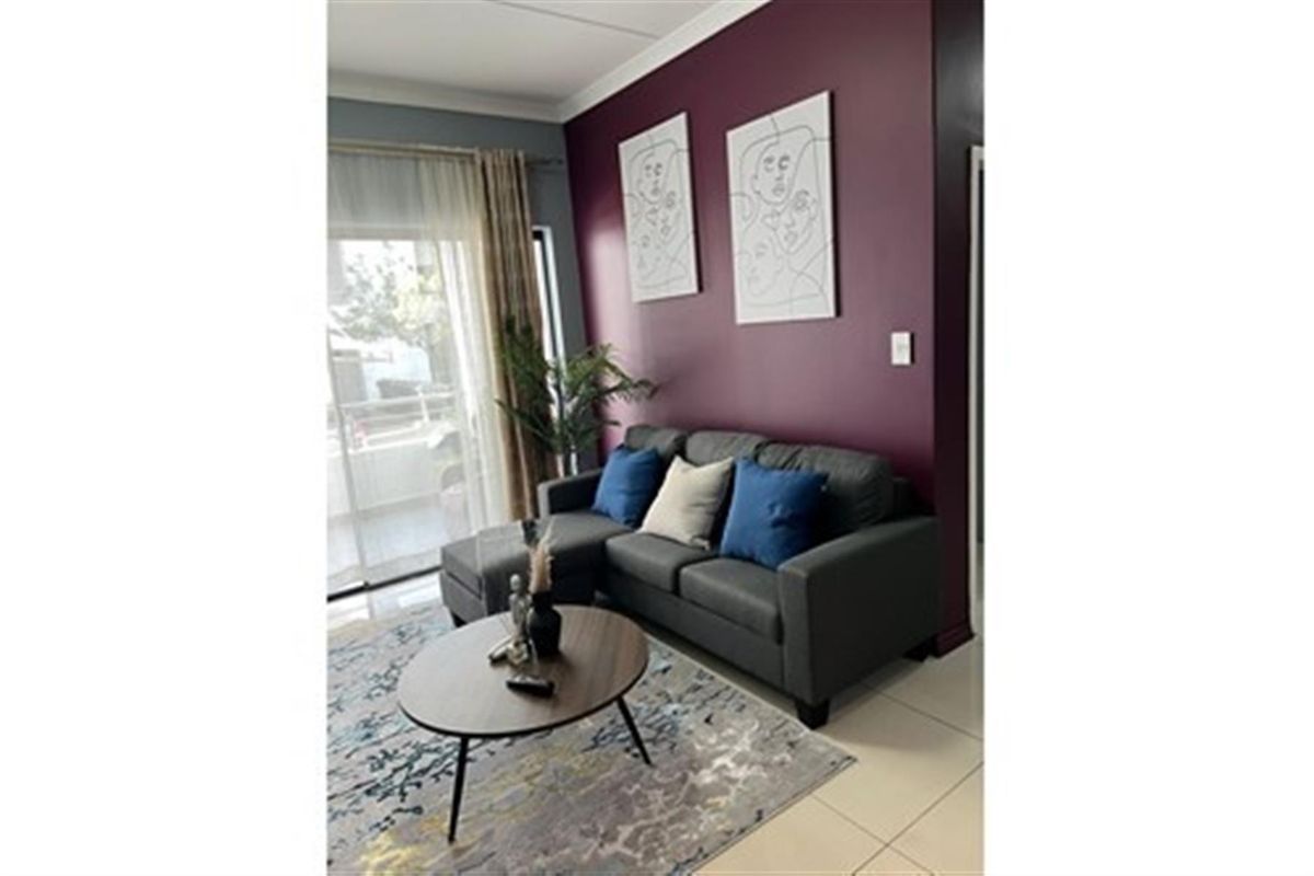 A living room area featuring tiled flooring and a sliding glass door providing access to an outdoor space.