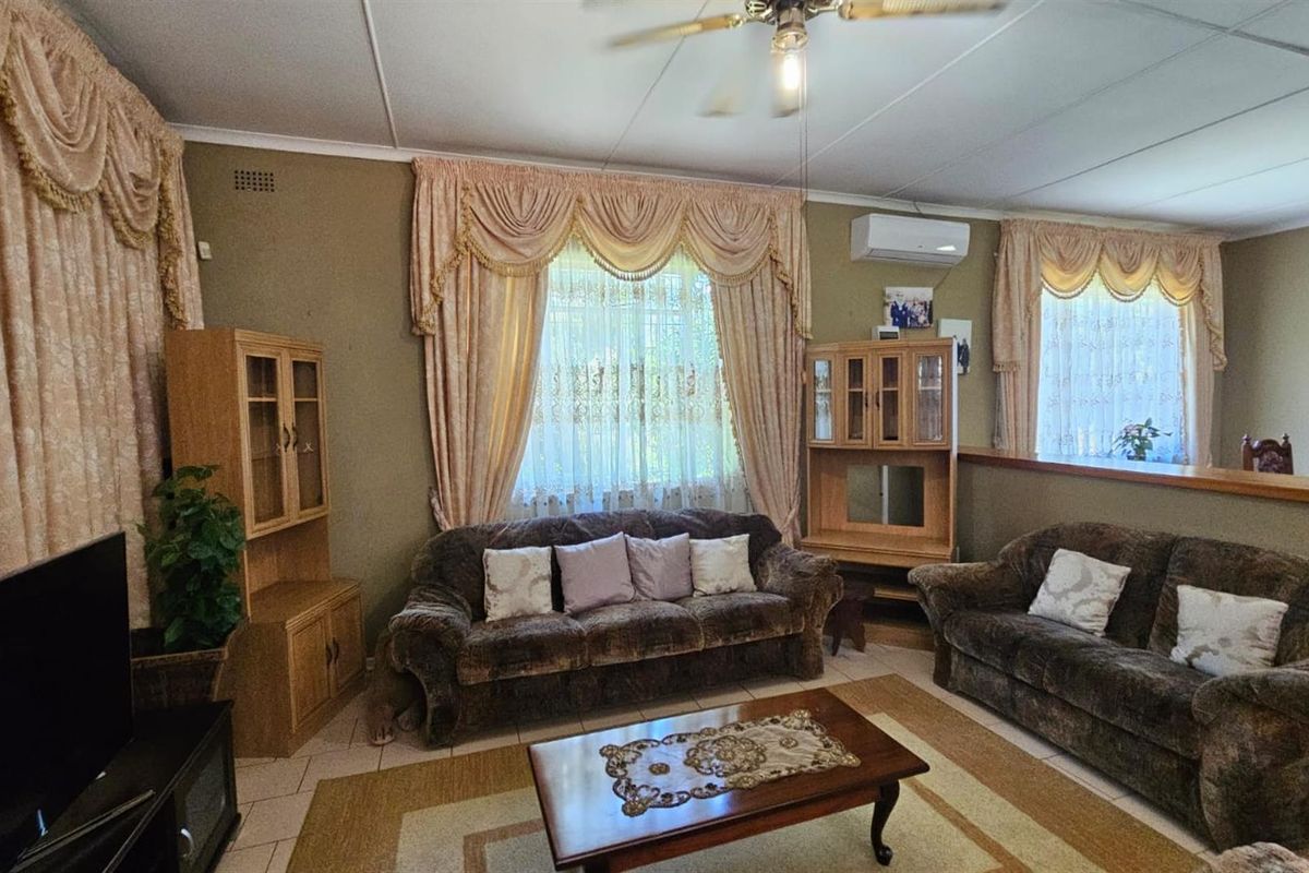 A living room featuring tiled flooring, a ceiling fan, and a wall-mounted air conditioning unit.