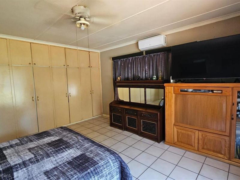 A bedroom featuring extensive built-in floor-to-ceiling cabinetry, tiled flooring, and a wall-mounted air conditioning unit.
