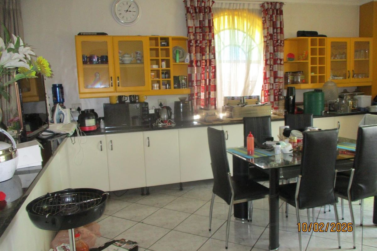 A functional kitchen featuring white base cabinetry, bright yellow wall-mounted cabinets, and tiled flooring, providing a practical workspace for daily use.