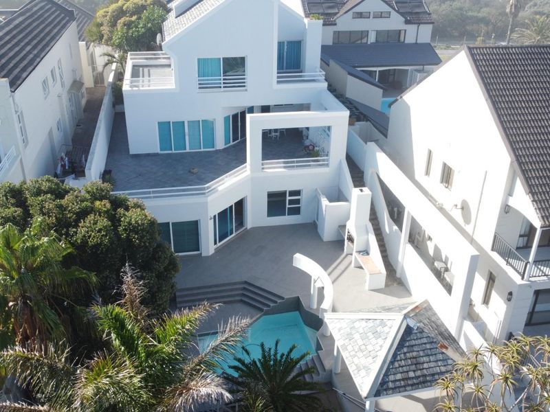Aerial view of a multi-level residential property featuring a swimming pool, paved courtyard, outdoor fireplace, and multiple balconies.