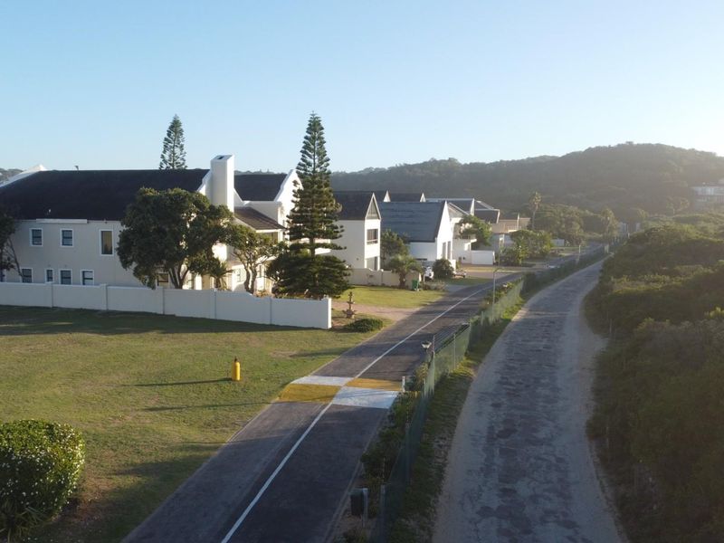 Aerial view of the property showing the surrounding neighborhood, paved access road, and landscaped grounds with perimeter walling.