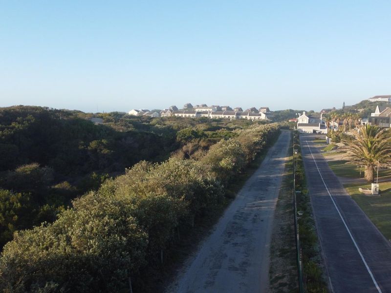 An elevated aerial view of the coastal estate, showcasing the surrounding landscape, local road infrastructure, and nearby residential properties.