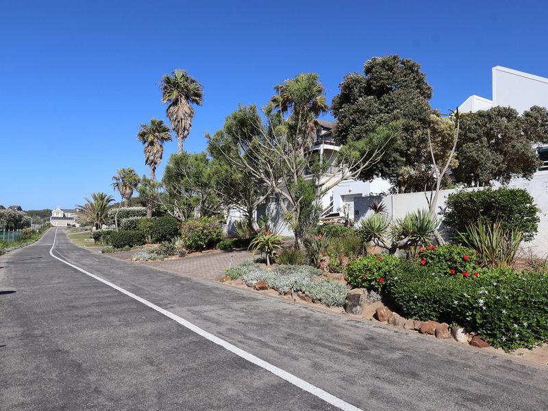A view of the property exterior from the street, showcasing the driveway, landscaped garden, and surrounding neighbourhood approach.