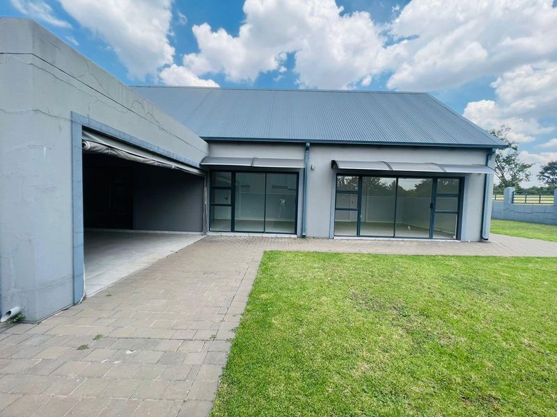 Rear view of the property featuring a paved patio area, large sliding glass doors, and a well-maintained lawn.