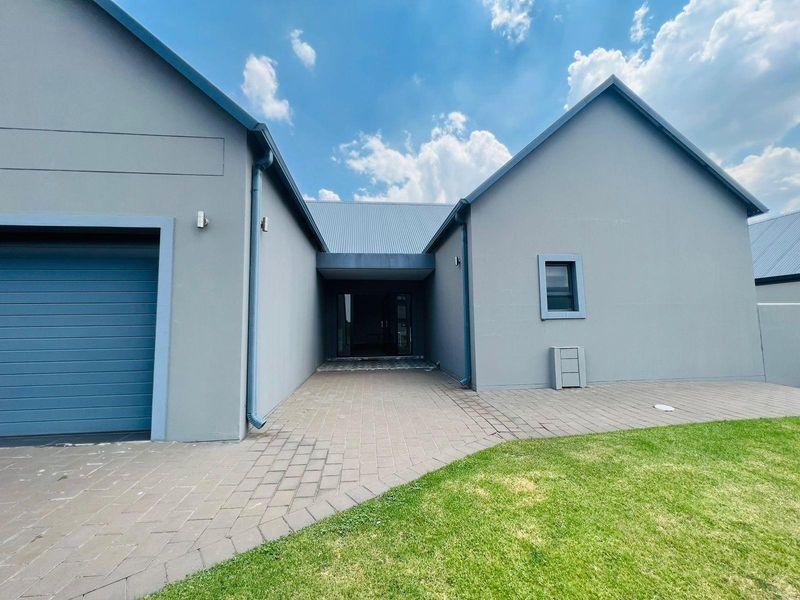 Modern exterior front elevation featuring a paved driveway, integrated garage, and a covered entrance walkway with contemporary grey finishes.
