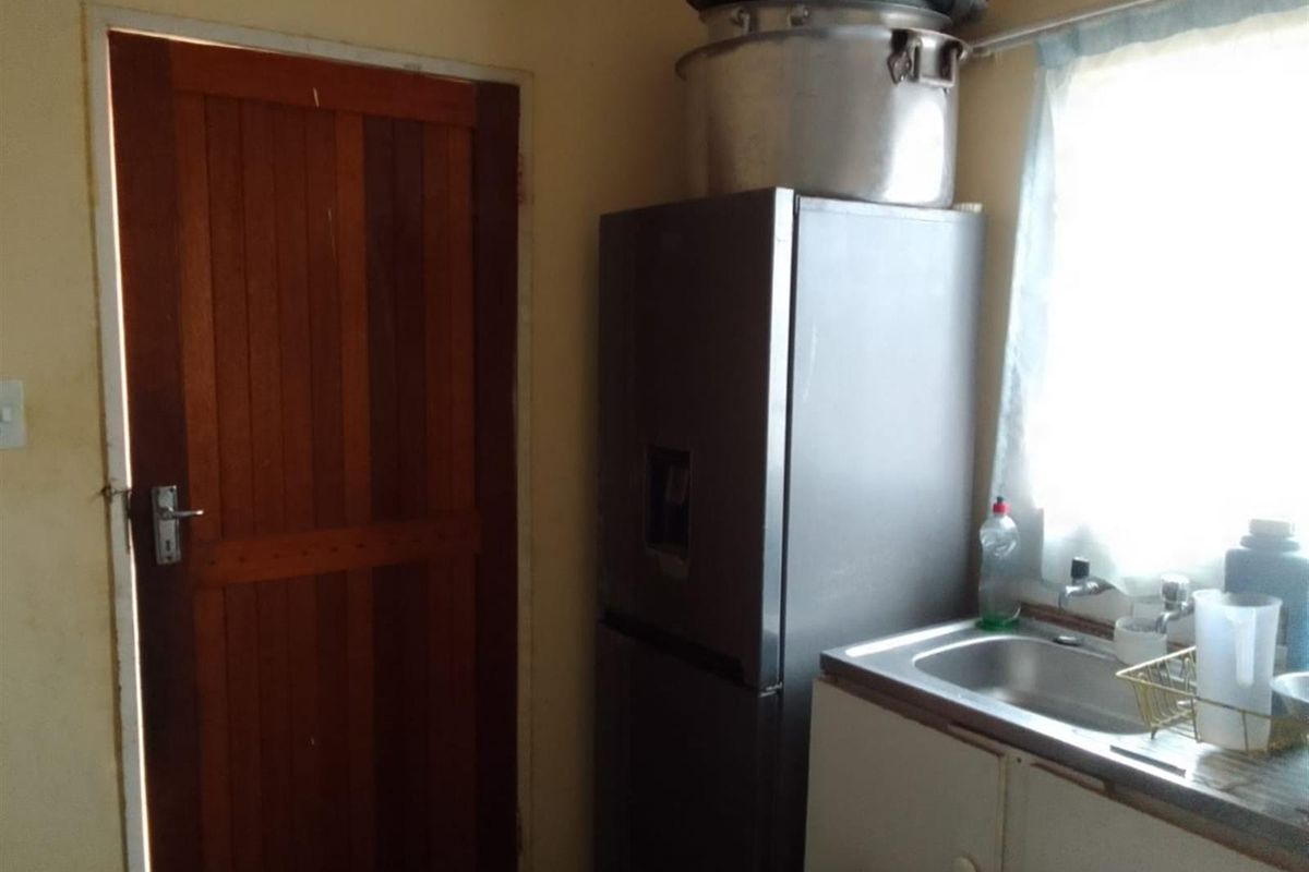 A functional kitchen area featuring a stainless steel sink, built-in cabinetry, and a wooden door leading to the exterior.
