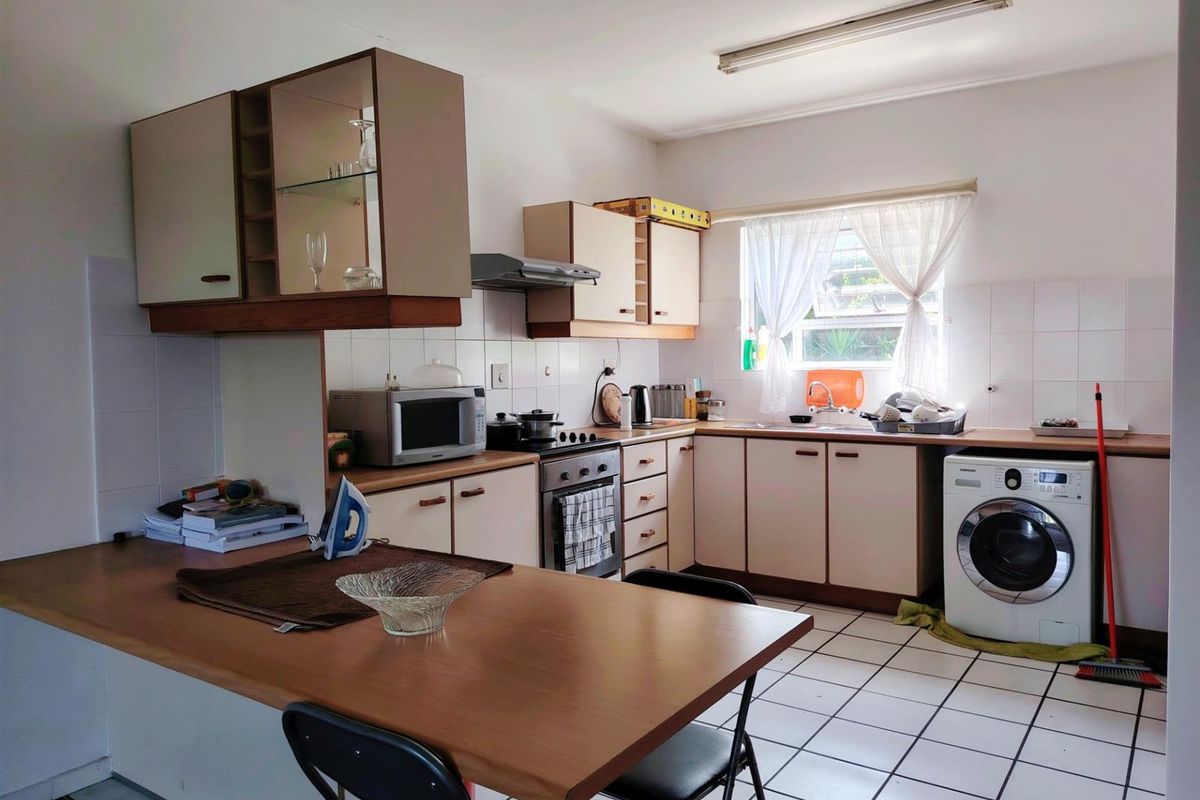 Functional kitchen featuring built-in cabinetry, laminate countertops, tiled backsplash, and an integrated washing machine, offering a practical layout for daily use.