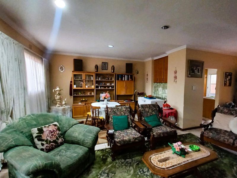 A spacious living area featuring coved cornicing, recessed lighting, and built-in cabinetry, offering a functional layout with potential for modern updates.