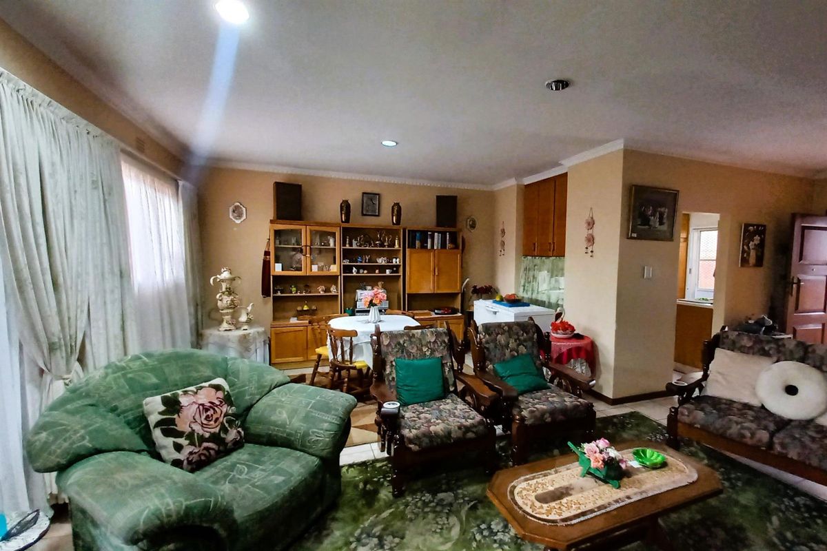 A spacious living area featuring coved cornicing, recessed lighting, and built-in cabinetry, offering a functional layout with potential for modern updates.