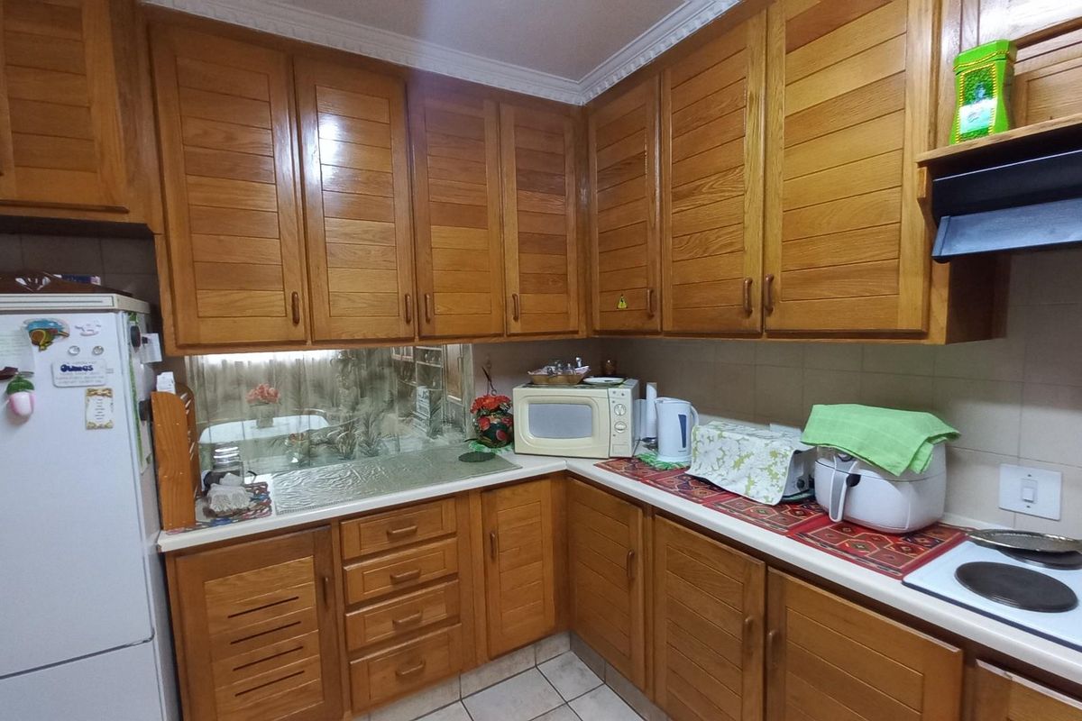 A functional kitchen featuring traditional wooden cabinetry, laminate countertops, and a tiled splashback, offering a classic aesthetic with ample storage space.