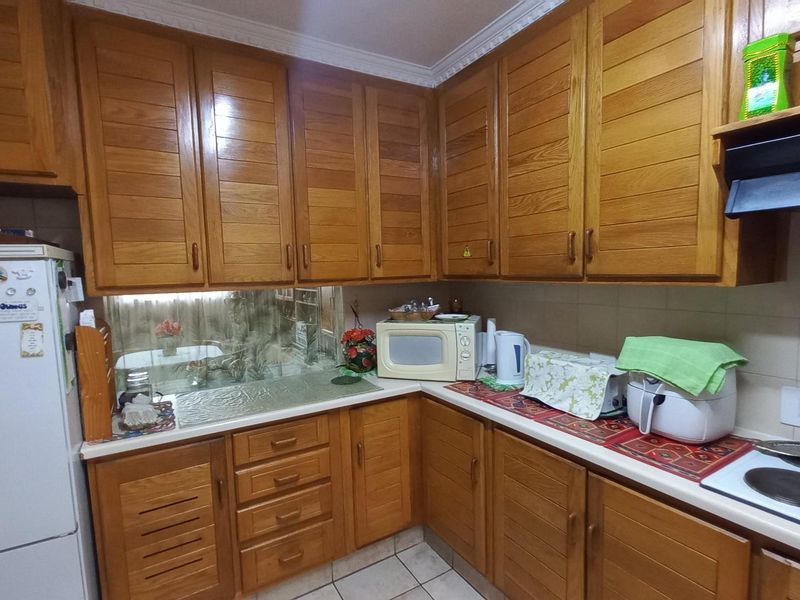 A functional kitchen featuring traditional wooden cabinetry, laminate countertops, and a tiled splashback, offering a classic aesthetic with ample storage space.