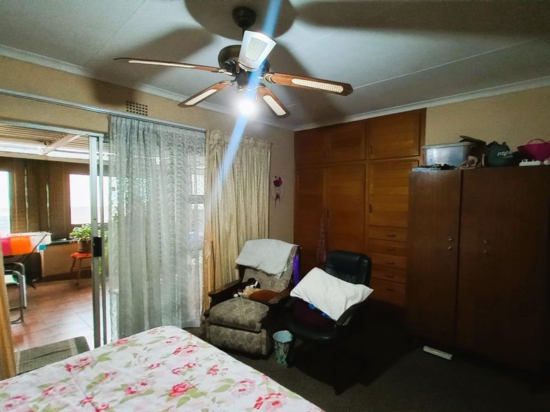 A bedroom featuring built-in wooden cupboards, a ceiling fan, and a sliding glass door providing access to an adjoining patio area.