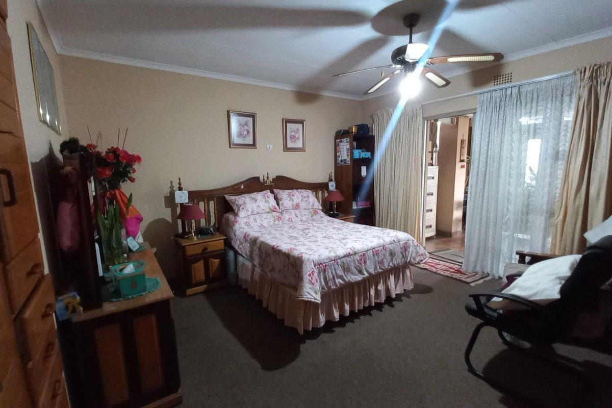 A carpeted bedroom featuring a ceiling fan, built-in wardrobe, and sliding glass door access to an adjoining space.