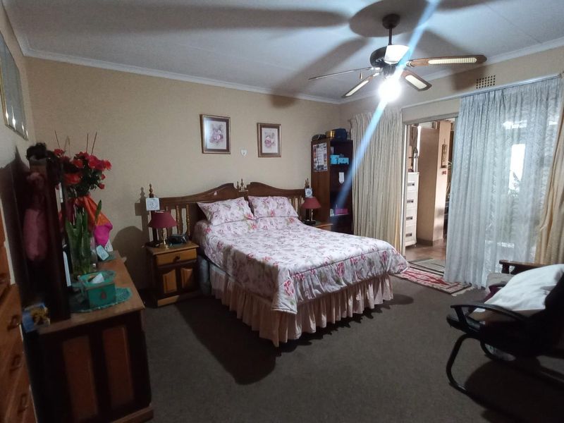 A carpeted bedroom featuring a ceiling fan, built-in wardrobe, and sliding glass door access to an adjoining space.