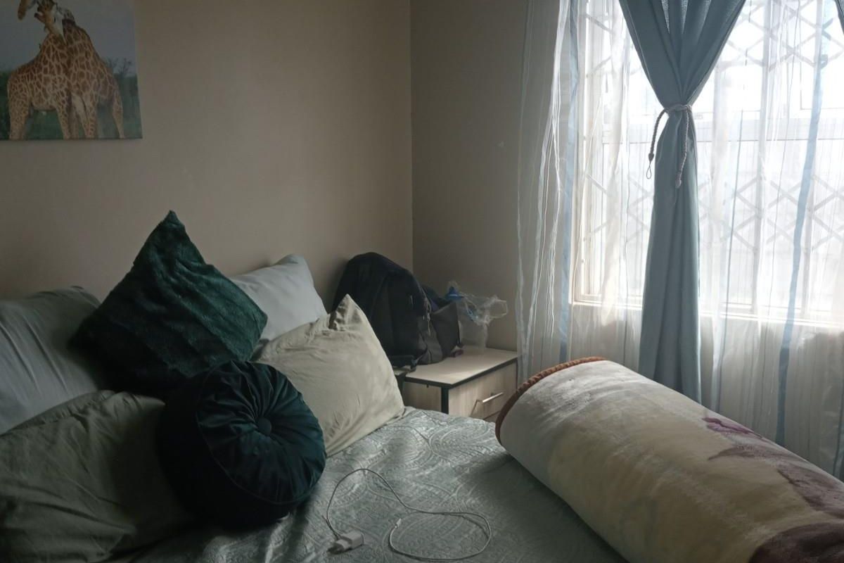 A standard bedroom featuring a window with an integrated security gate, providing natural light and essential security features.
