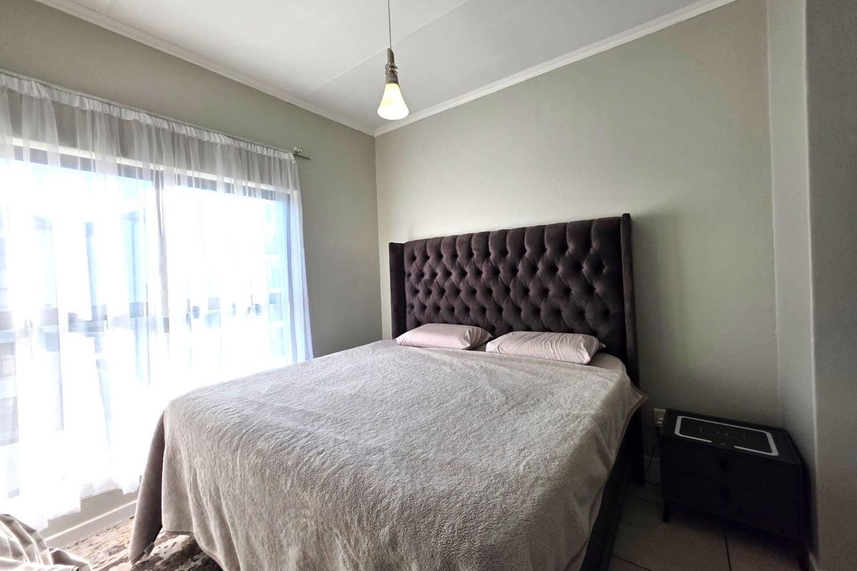 A well-lit bedroom featuring tiled flooring, a coved ceiling, and a large sliding glass door providing natural light.