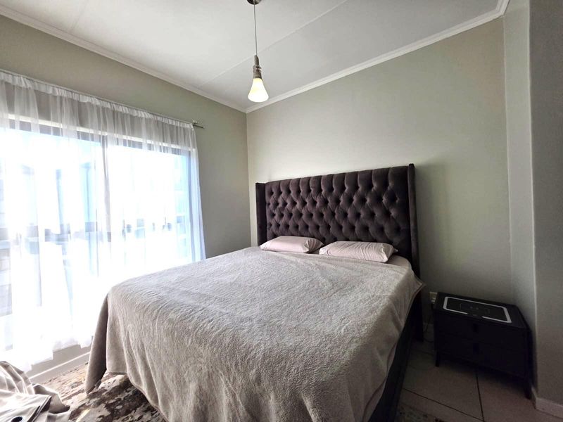 A well-lit bedroom featuring tiled flooring, a coved ceiling, and a large sliding glass door providing natural light.