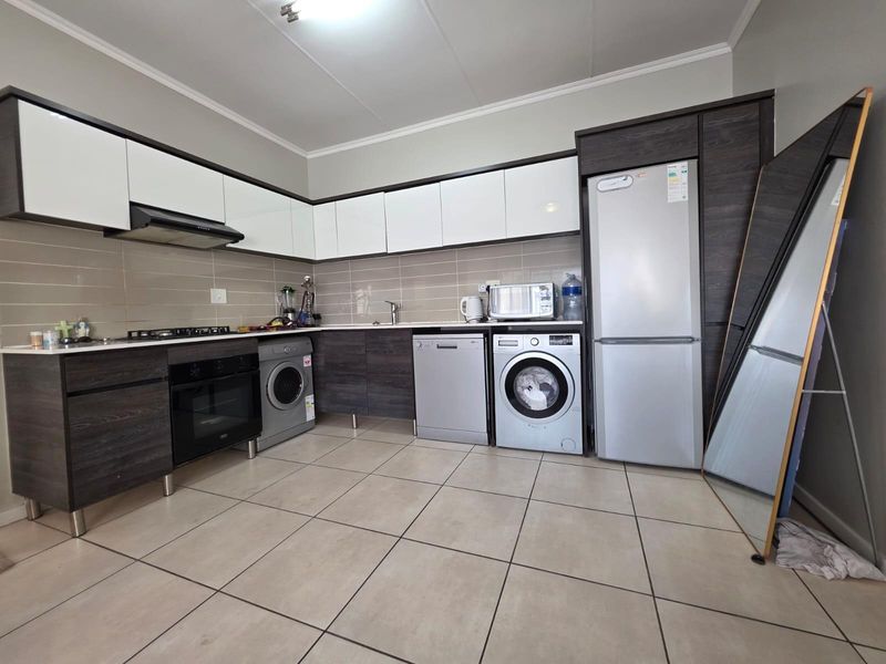 Modern kitchen featuring dark wood and white cabinetry, tiled backsplash, gas hob, extractor fan, and integrated space for multiple appliances.
