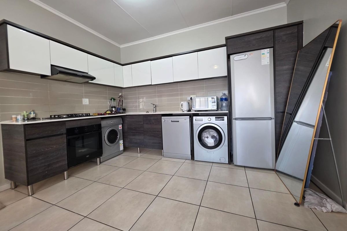 Modern kitchen featuring dark wood and white cabinetry, tiled backsplash, gas hob, extractor fan, and integrated space for multiple appliances.