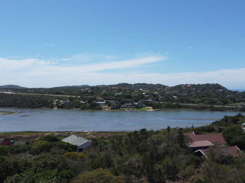 A scenic elevated view overlooking a coastal lagoon, surrounding natural vegetation, and distant residential properties.