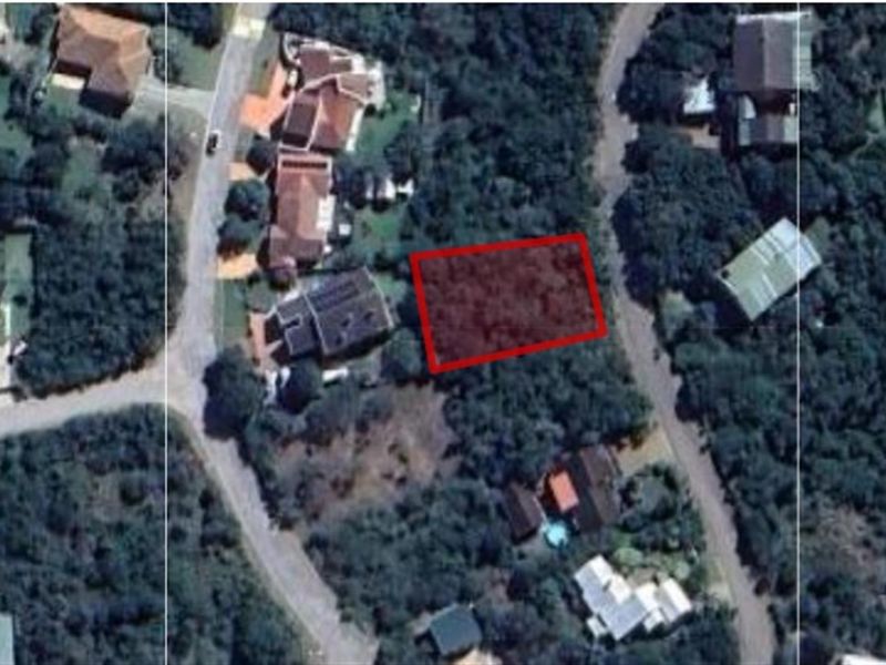 Aerial view of a vacant residential plot highlighted in red, situated within a developed suburban neighborhood with established vegetation.