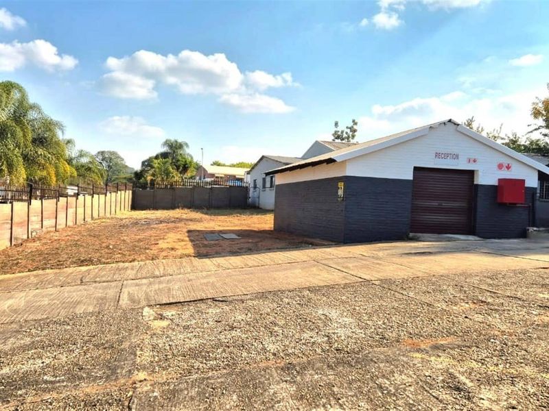 Commercial property exterior featuring a reception building, large concrete paved area, and perimeter walling.