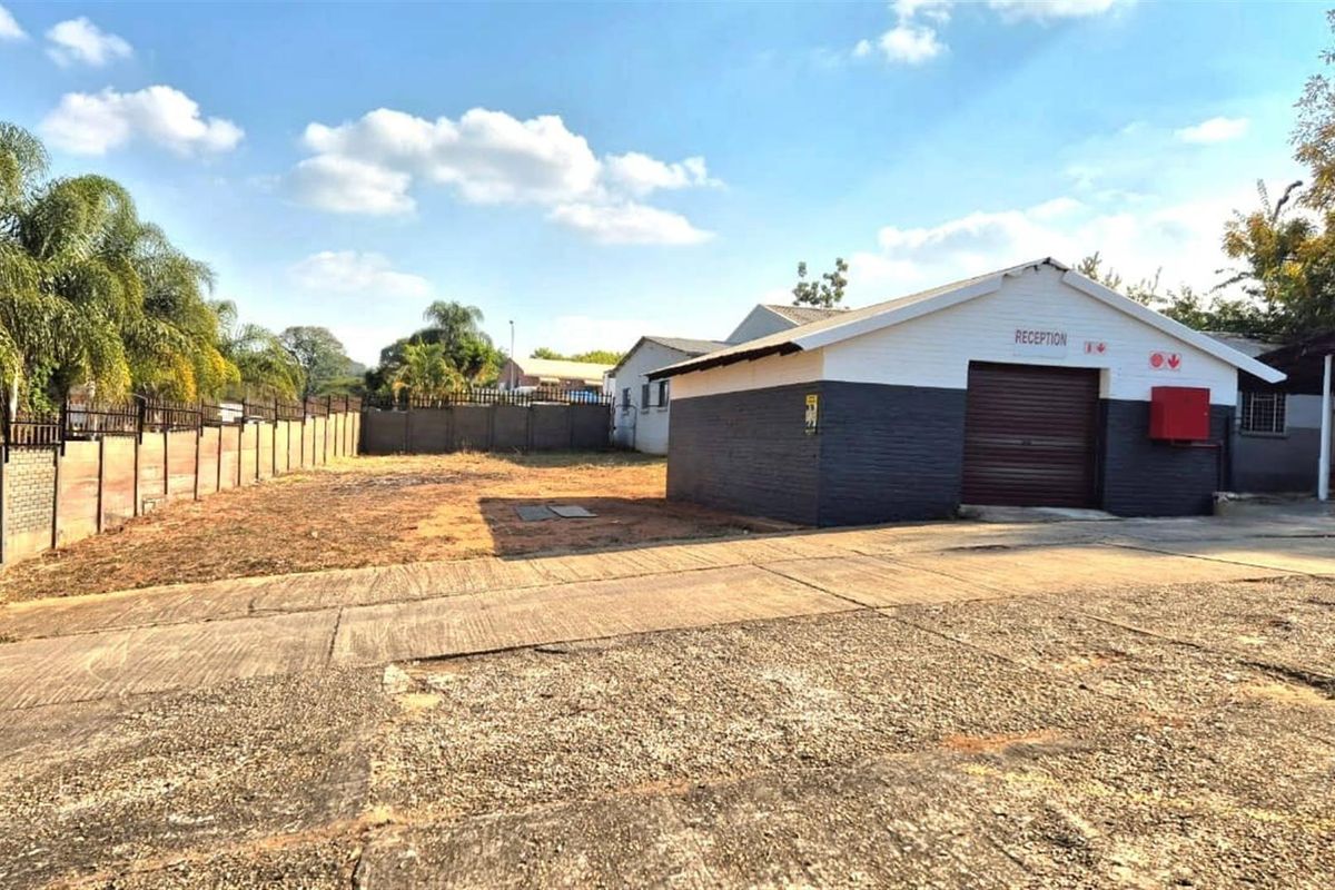 Commercial property exterior featuring a reception building, large concrete paved area, and perimeter walling.
