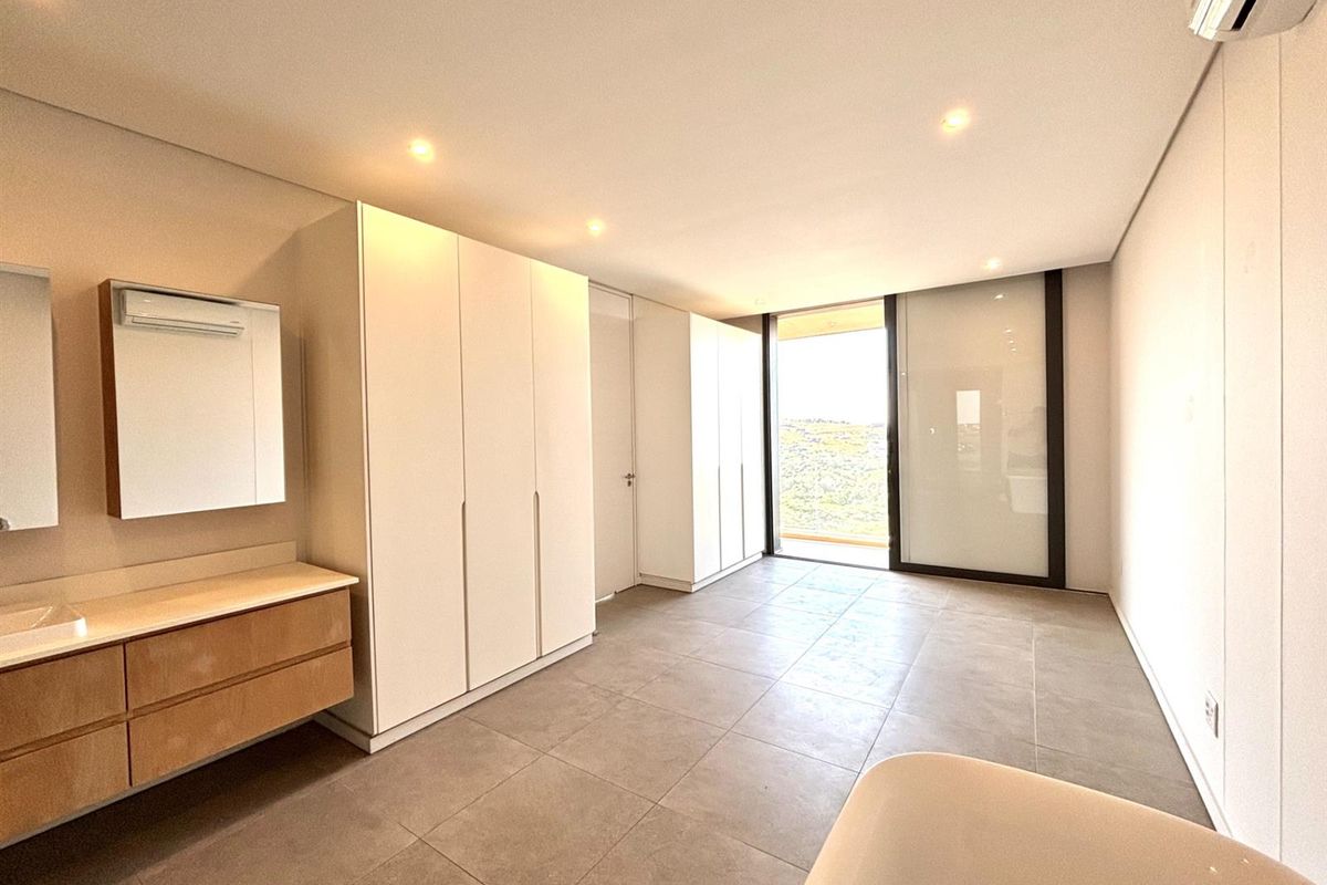 Modern bedroom featuring built-in cabinetry, tiled flooring, recessed lighting, and direct access to a private balcony with scenic views.