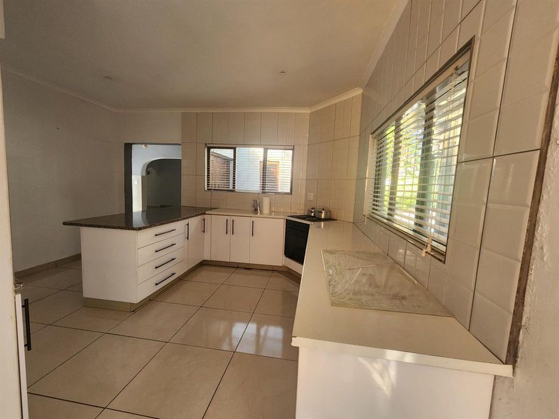 A functional kitchen featuring white cabinetry, granite countertops, tiled backsplash, and built-in cooking appliances, offering a clean and neutral space ready for updates.