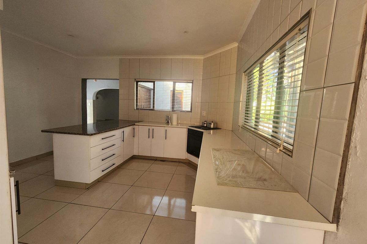 A functional kitchen featuring white cabinetry, granite countertops, tiled backsplash, and built-in cooking appliances, offering a clean and neutral space ready for updates.