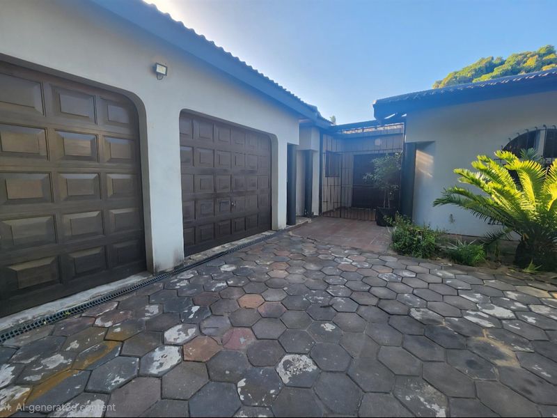 Front exterior view featuring a double garage with paved driveway and secure gated entrance area.