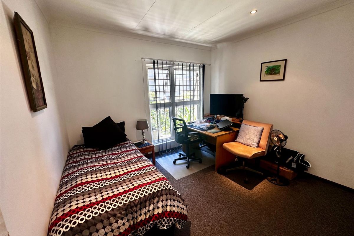 A functional bedroom featuring carpeted flooring, a window with security bars, and recessed ceiling lighting.