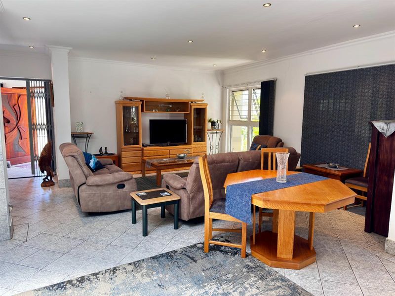 Spacious open-plan living and dining area featuring tiled flooring, recessed downlighting, and a neutral color palette.