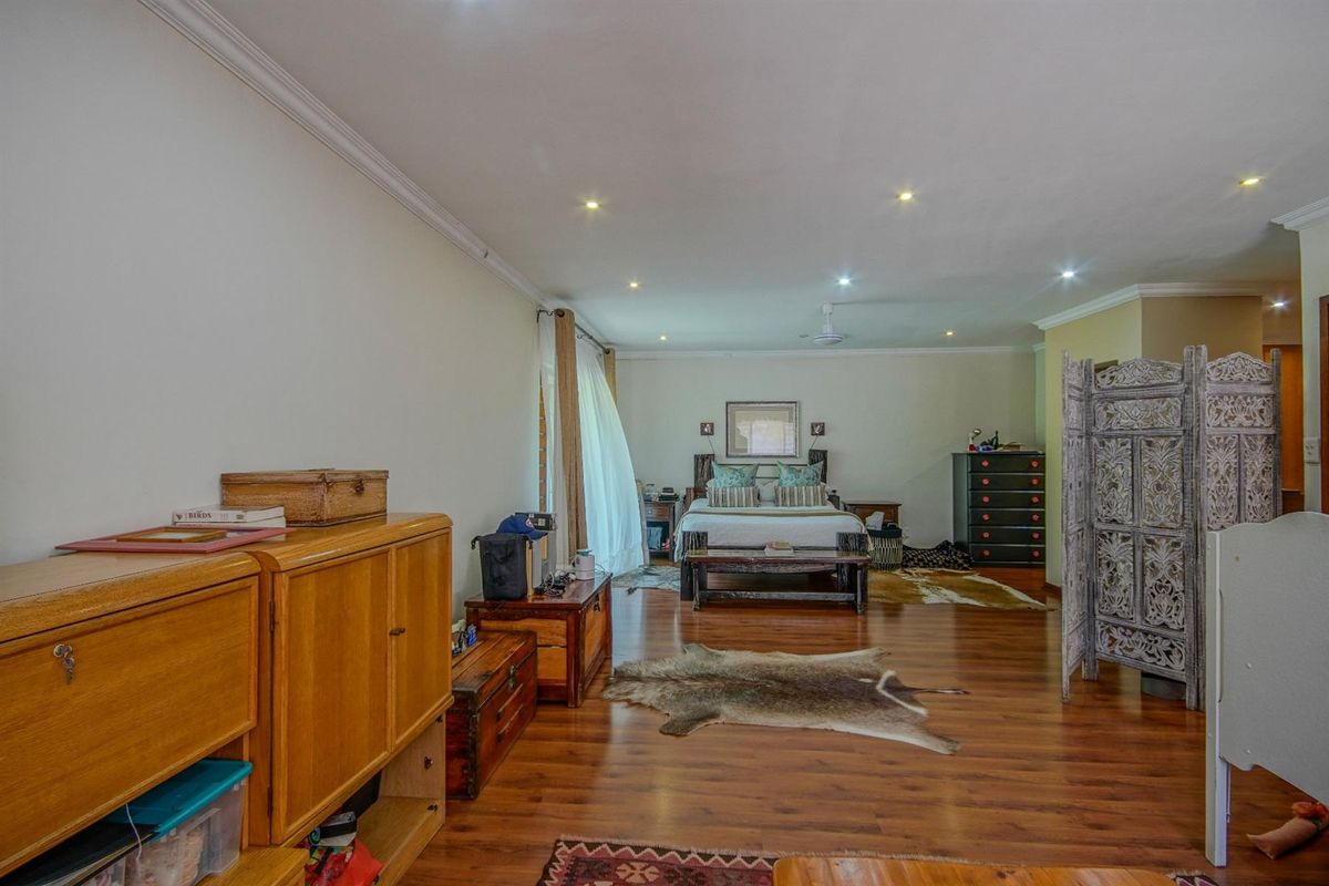 Spacious bedroom featuring warm-toned laminate flooring, recessed ceiling lighting, and crown molding, offering a comfortable and well-lit living space.